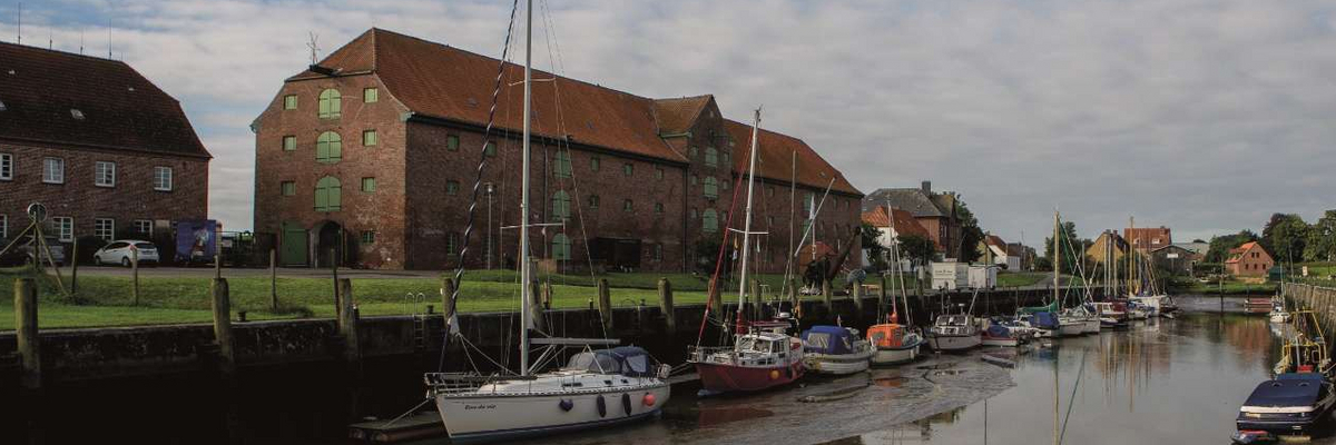 Sicht auf den Tönninger Hafen mit Booten und dem historischen Packhaus in der linken Bildhälfte