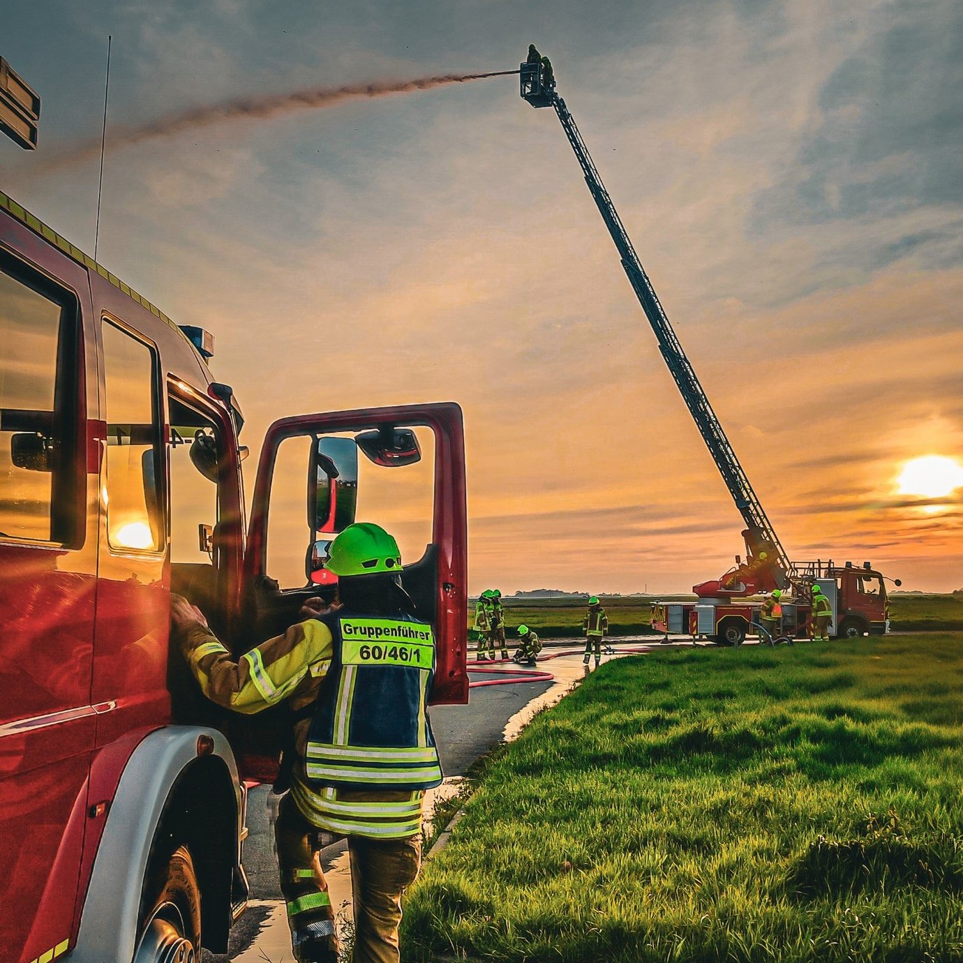 Schlauchübung von Drehleiter in großer Höhe vor Sonneuntergang