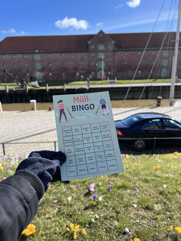 linke Hand hält einen Müll-Bingo-Zettel